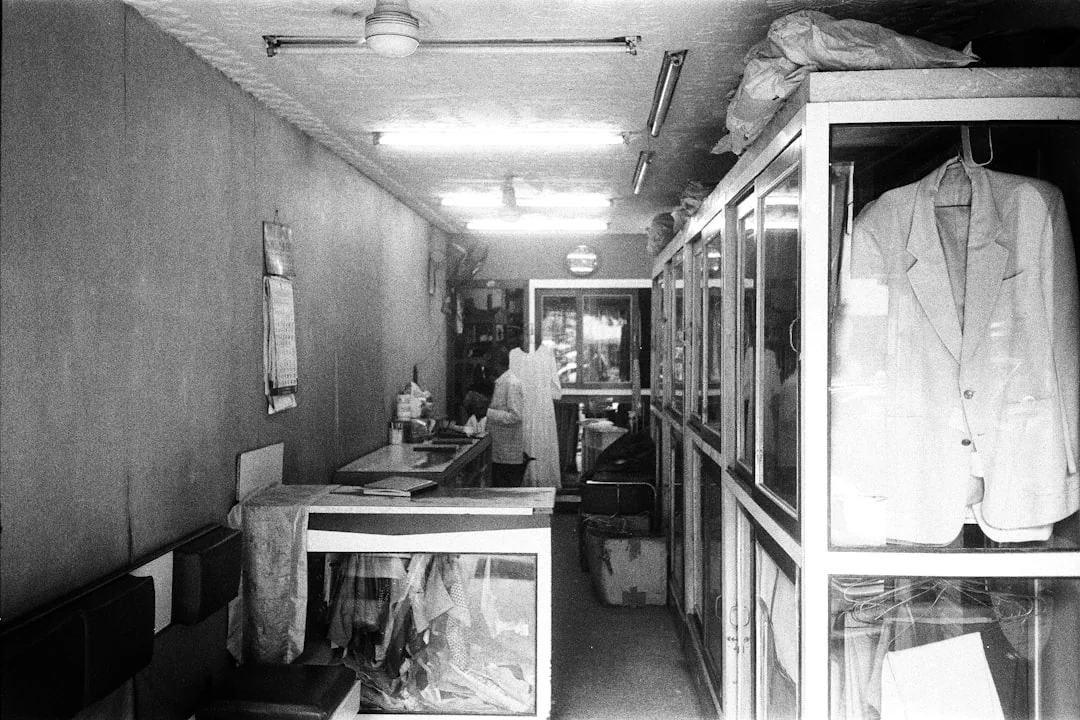 A man cleaning a glass door indoors using a spray bottle and cloth.